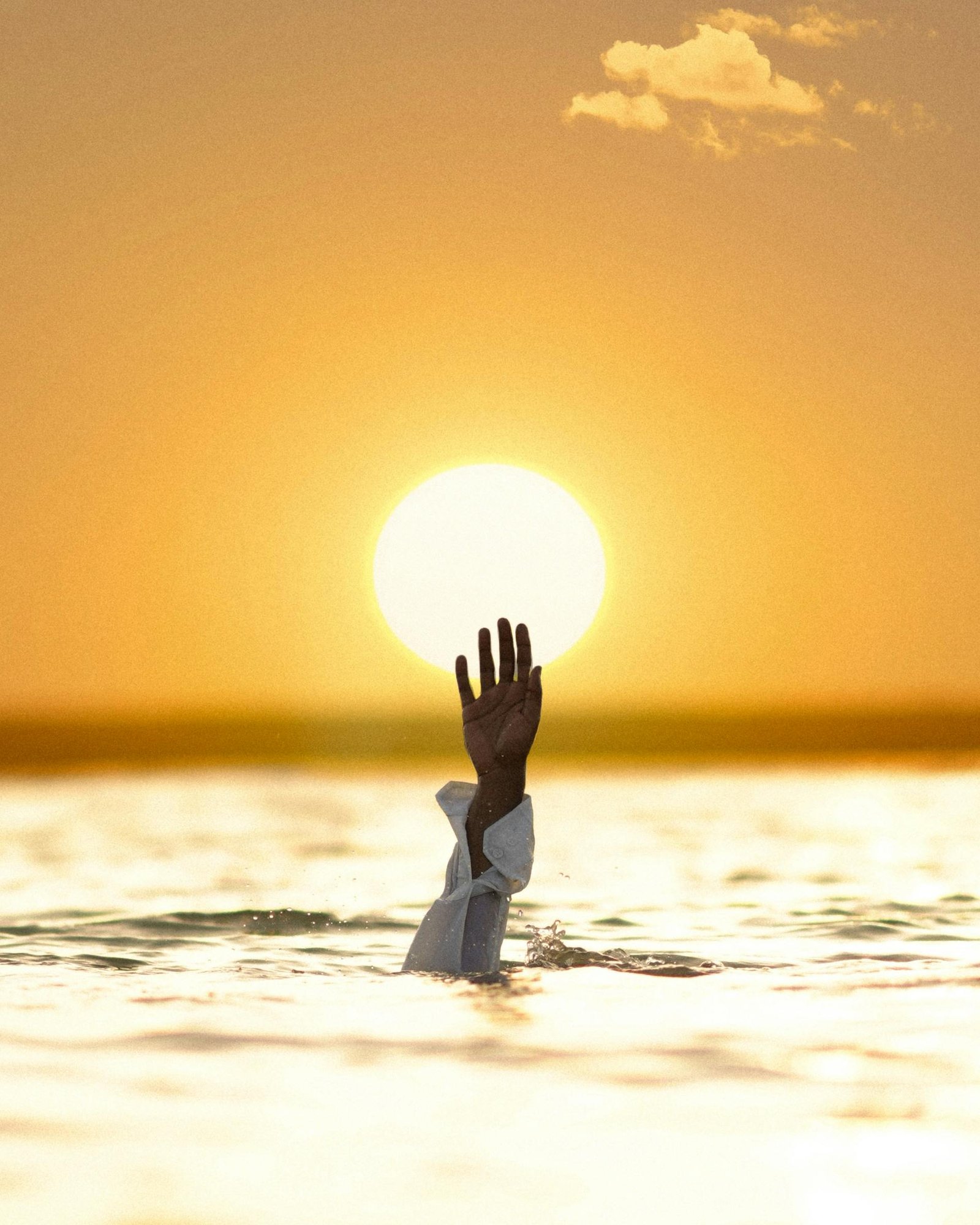 A dramatic image of a hand reaching out of water towards a setting sun, symbolizing hope.