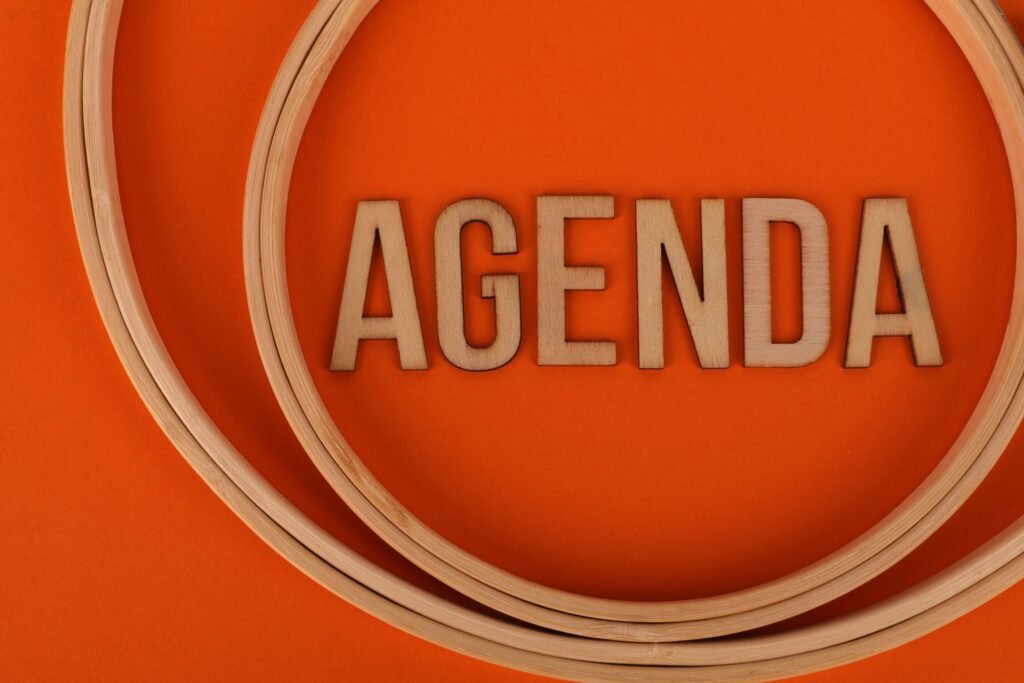 Wooden letters spelling 'agenda' surrounded by circular frames on an orange background.